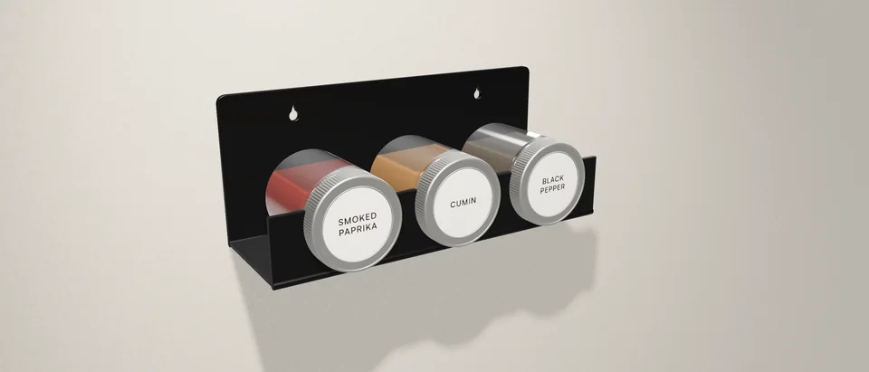 A gloss black Verge Triad on a plaster wall, holding three spice jars with their lids facing out.