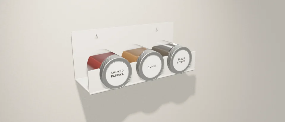 A white Verge Triad on a plaster wall, holding three spice jars with their lids facing out.