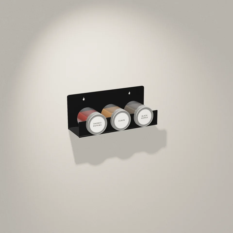 A gloss black Verge Triad on a plaster wall, holding three spice jars with their lids facing out.